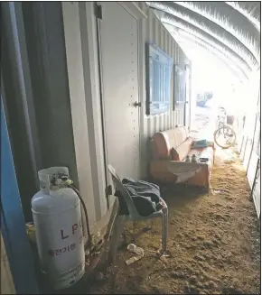  ??  ?? A propane gas tank, chair and sofa are placed next to a shipping container, a makeshift home for migrant workers at a farm in Pocheon. Workers often are crammed in shipping containers or flimsy, poorly ventilated huts.