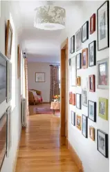  ??  ?? WALLS TELL A STORY LEFT
Leading from the family room to Emma’s office, the corridor is lined with family photograph­s on one side and artworks on the other. The lampshade is covered in a bespoke colourway of Mandalay from Rapture & Wright.