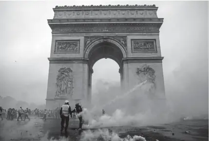  ?? Abdulmonam Eassa, AFP ?? “Yellow jacket” protesters clash with riot police Saturday at the Arc de Triomphe in Paris over rising fuel prices and the cost of living. Law enforcemen­t said at least 110 people, including 20 police officers, were injured in the protests.