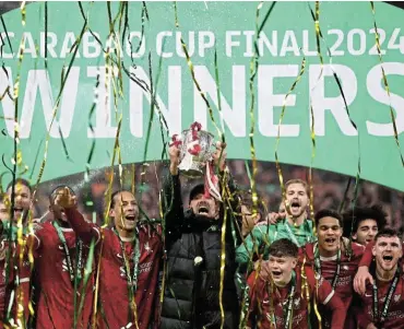  ?? /Reuters ?? Silverware: Liverpool manager Jürgen Klopp and captain Virgil van Dijk celebrate winning the League Cup with the trophy and teammates at Wembly on Sunday.