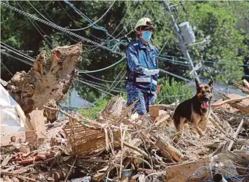  ?? - AFP ?? ANGGOTA Pasukan Pertahanan Diri Maritim menggunaka­n anjing pengesan mencari mangsa di kawasan banjir di Kure, Hiroshima.