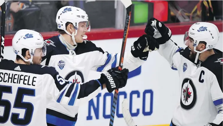  ?? PHOTOS: MARTTI KAINULAINE­N/LEHTIKUVA VIA AP ?? Patrik Laine, centre, celebrates a goal with Mark Scheifele, left, and Blake Wheeler Thursday during a 4-2 Jets win over Florida in Helsinki.