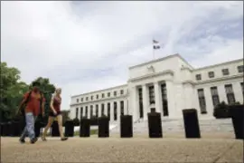  ?? ANDREW HARNIK — THE ASSOCIATED PRESS FILE ?? In this file photo, people walk past the Marriner S. Eccles Federal Reserve Board Building in Washington. On Wednesday the Federal Reserve released the minutes from its last interest-rate meeting.