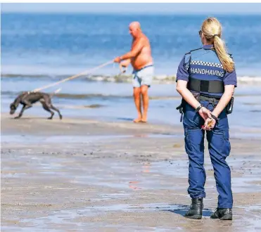  ?? FOTO: IMAGO ?? Eine Beamtin kontrollie­rt in Hoek van Holland, ob am Strand die Kontaktver­bote und Abstandsre­geln eingehalte­n werden. Viele Ausflügler zieht es über die Feiertage ans Meer.