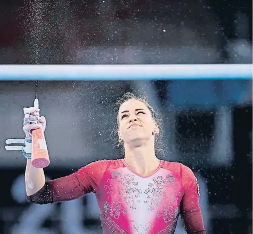  ??  ?? La gimnasta húngara Zsofia Kovacs desinfecta las barras paralelas antes de ensayar su a ejercicio