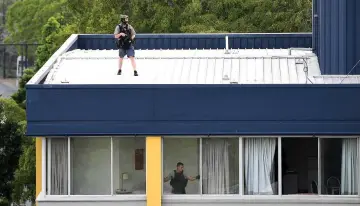  ?? — Reuters photo ?? Special Emergency Response Team (SERT) police officers can be seen on the roof and inside an apartment at a unit block in the area known as Auchenflow­er in central Brisbane where two men barricaded themselves.