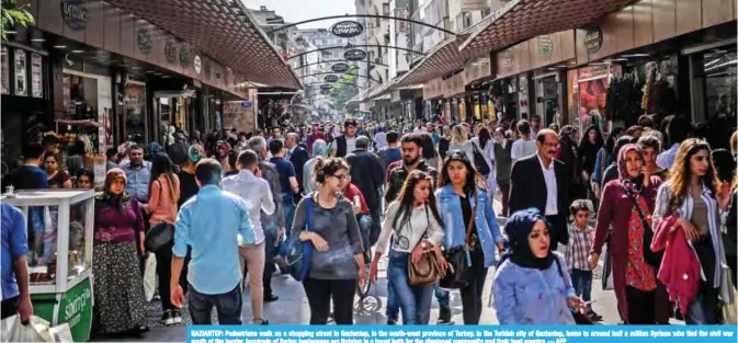  ?? — AFP ?? GAZIANTEP: Pedestrian­s walk on a shopping street in Gaziantep, in the south-west province of Turkey. In the Turkish city of Gaziantep, home to around half a million Syrians who fled the civil war south of the border, hundreds of Syrian businesses are...