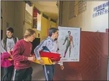  ??  ?? Pupils holding red capes and a sword arrive at the school. The school was closed from March to August when Spain went into one of the world’s strictest confinemen­ts to stem the spread of the covid-19 pandemic.