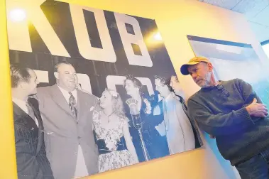  ?? ADOLPHE PIERRE-LOUIS/JOURNAL ?? T.J. Trout examines a historical poster in the hallway of KKOB-AM radio. The photo for the poster was taken in 1941 to celebrate KKOB-AM’s fifth year as an NBC affiliate. Pictured second from left is Don Wilson, an announcer and voice actor on comedian Jack Benny’s syndicated radio program, which aired on KKOB-AM. To Wilson’s left is actress Martha Tilton. They are surrounded by KKOB-AM staff