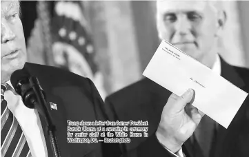  ??  ?? Trump shows a letter from former President Barack Obama at a swearing-in ceremony for senior staff at the White House in Washington, DC. — Reuters photo