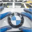  ?? FOTO: ARMIN WEIGEL ?? Ein Mitarbeite­r montiert ein BMWEmblem. Der bayrische Fahrzeughe­rsteller gilt als profitabel­ster Autobauer.