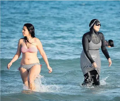  ??  ?? In Tunesien planschen Damen in Bikini und Burkini vorerst nicht einträchti­g nebeneinan­der. Für viele arabische Frauen ist der Burkini ein Fortschrit­t ins Wasser.