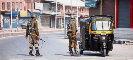  ?? — Reuters ?? Heightened vigilance: Indian police officers stopping an auto-rickshaw driver for inspection during the strike in Kashmir.