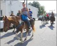  ?? (NWA Democrat-Gazette/David Gottschalk) ?? A horseback rider participat­es in the Harrison Roundup Club’s wagon train Friday through downtown Harrison.