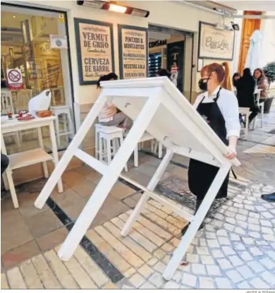  ?? JAVIER ALBIÑANA ?? Una camarera retira una mesa de una terraza de un bar del centro de Málaga