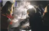  ?? VAGGELIS KOUSIORAS AP ?? Red Cross workers distribute food to residents staying overnight on a field after a large quake in Greece.