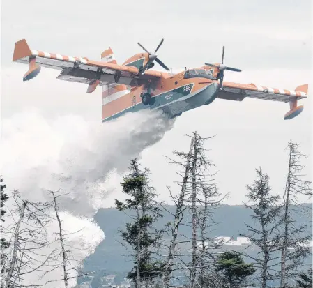  ?? JOE GIBBONS/THE TELEGRAM ?? A provincial Department of Natural Resources water bomber flies behind the Rainbow Riders facility on Mount Scio Road to drop water onto a forest fire Tuesday.