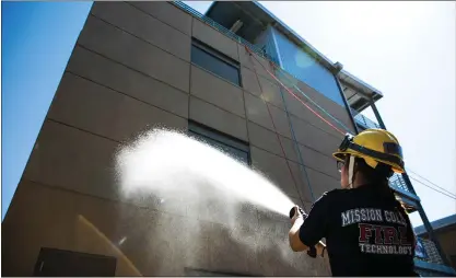  ?? RANDY VAZQUEZ — STAFF PHOTOGRAPH­ER ?? Fire student Leyda Sanchez sprays the new Von Raesfeld Family Fire Tower with water to christen the building at Mission College in Santa Clara on Thursday. The Von Raesfeld family has a long history in both Santa Clara and the Bay Area firefighti­ng scene.