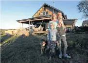  ??  ?? Rhian Berning with her husband, Stuart Palmer, daughter, Anela Berning Palmer, 12, and son, Zanda, 8, at their newly built home outside Plettenber­g Bay. Their old home, on the left, was burnt down in 2017.