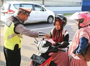  ??  ?? BAGAS BIMANTARA/JAWA POS RADAR MADIUN NEKAT: Polisi memberikan surat tilang kepada pelajar putri di Kota Madiun kemarin.