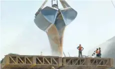  ?? — Reuters ?? Workers stand as a crane loads wheat onto a ship at Mundra Port in the western Indian state of Gujarat.