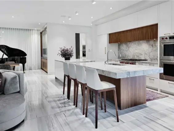  ??  ?? This page A collaborat­ion between 2H Interior Design, Hobin Architectu­re, and Irpinia Kitchens, this sophistica­ted lounge kitchen is at once bold and graceful. Lacquered high-gloss cabinetry is paired with custom stained walnut, while veined marble...