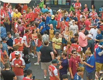  ?? KIM HAIRSTON/BALTIMORE SUN ?? Arsenal supporters gather on Saturday night near Abbey Burger Bistro in Federal Hill for a block party before the preseason friendly against Everton at M&T Bank Stadium.