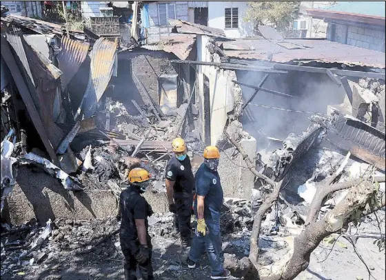  ?? BOY SANTOS ?? Rescue workers look at the crash site in Plaridel, Bulacan, where 10 people were killed when a small plane crashed into a house while trying to take off.