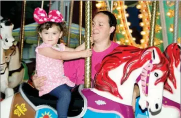  ??  ?? Ava Easterling, aided by her mother Allison, rides the carousel during the 2016 Toad Suck Daze festival in Conway.