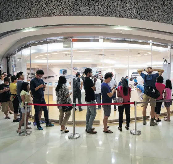  ?? BRYAN VAN DER BEEK / BLOOMBERG ?? Customers wait in line to look at Apple Watch devices on display at a Singapore mall. Singapore is testing new waters with its launch of a five-year plan this year to streamline its infrastruc­ture and reduce bureaucrac­y with sensor and facial recognitio­n technology.