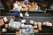  ?? Michael Ciaglo photos / Houston Chronicle ?? UPS workers sort packages and walk the box line at a company hub in Houston.