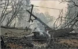  ?? Brian van der Brug Los Angeles Times ?? BURNED UTILITY poles and downed wires block Bald Rock Road in early September after the Bear fire ripped through Berry Creek in Butte County.