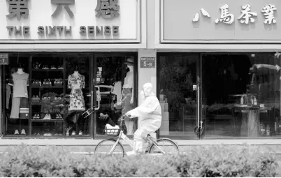  ?? AP ?? A worker in a protective suit rides a bicycle past shuttered retail shops after authoritie­s ordered the closing down of non-essential businesses and asked people to work at home in the Chaoyang district on Monday.