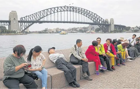  ?? REUTERS ?? Chinese tourists rest near the Harbour Bridge in Sydney.