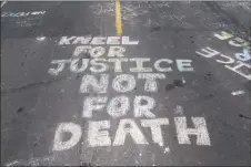  ?? Stephen Maturen / Getty Images ?? “Kneel for Justice not for Death” is written on the road outside the Cup Foods, where George Floyd was killed in police custody in Minneapoli­s.