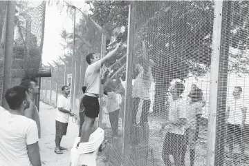  ??  ?? Detainees fixing a perimeter fence at the Manus Island detention centre in Papua New Guinea.