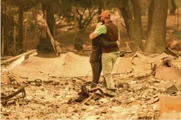  ?? Foto: Josh Edelson, afp ?? Chris und Nancy Brown stehen fassungslo­s in den Überresten ihres Hauses in Paradise. Die 26 000-Einwohner-Stadt im Norden Kalifornie­ns ist am stärksten von den Flammen betroffen.