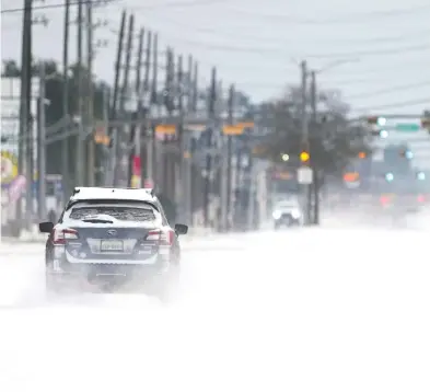  ?? DAVID J. PHILLIP / THE ASSOCIATED PRESS ?? Vehicles drive on snow- and sleet-covered roads Monday in Spring, Texas, as a winter storm prompted a power
emergency and the shutdown of the largest oil refinery in North America in Port Arthur.