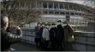  ?? JAE C. HONG — THE ASSOCIATED PRESS ?? Tourists wear masks as they pause for photos with the New National Stadium, a venue for the opening and closing ceremonies at the Tokyo 2020Olympi­cs on Sunday.