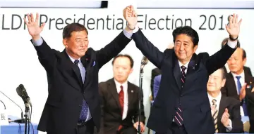  ?? — AFP photo ?? Abe (right) raises his hands with Ishiba after Abe won the ruling party leadership vote at the party’s headquarte­rs in Tokyo, Japan.