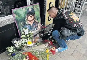  ?? / SANDILE NDLOVU ?? Tattoo artist Conrad Cornelisse­n places a candle outside Nick Durandt's tattoo parlour in Norwood yesterday.