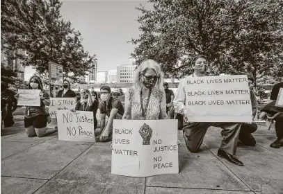  ?? Photos by Steve Gonzales / Staff photograph­er ?? Jani Maselli takes a knee to acknowledg­e the eight minutes and 46 seconds that Derek Chauvin knelt into the neck of George Floyd. Public defenders and attorneys gathered Monday to protest the death of the former Houston resident.