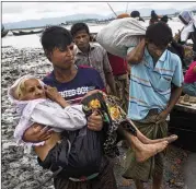  ?? BERNAT ARMANGUE / AP ?? A member of the Rohingya minority of Myanmar carries an elderly woman into Bangladesh from a boat Saturday, two of tens of thousands who reportedly crossed within 24 hours to flee violence in Myanmar.