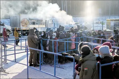  ?? ?? Migrants queue to receive hot food Dec. 22 at the Bruzgi checkpoint logistics center.