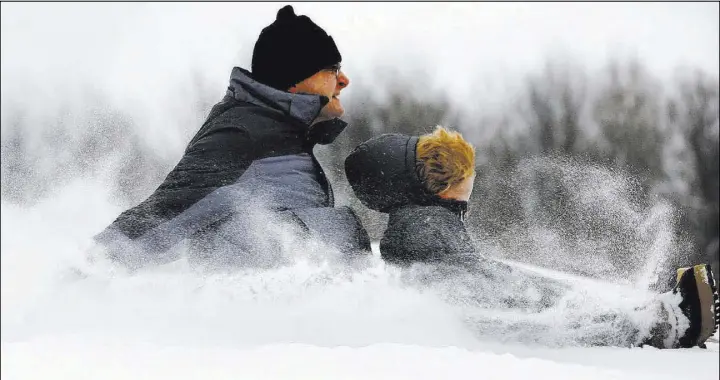  ?? STEPHANIE ZOLLSHAN/THE BERKSHIRE EAGLE VIA AP ?? Todd Clark and his son, Sawyer, 4, feel the snow on their faces Saturday during their first sledding of the season at Reid Middle School in Pittsfield, Mass. A winter storm of snow, freezing rain and bone-chilling temperatur­es hit the nation’s...