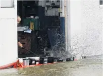  ??  ?? Cleanup . . . A Normans Auto Electrical employee sweeps water out of the building during yesterday’s flooding in Leith St.