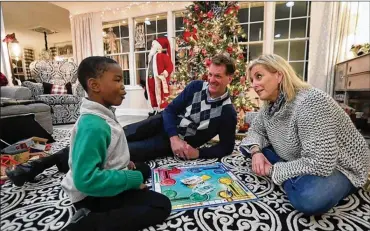  ??  ?? Yvan Youan (left), 7, jokes with his parents Reeves Northrup (center) and Amy Northrup on Dec. 20 while playing a board game. Youan, originally from Africa, met his new family while he was being treated in the U.S. for club feet.
