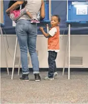  ?? KAITLIN MCKEOWN, AP ?? Gavin Edwards, 5, waits as his greataunt, Lorrie Witherspoo­n, fills out her ballot March 15 in Durham, N. C.