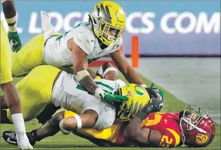  ?? Photograph­s by Luis Sinco Los Angeles Times ?? USC TAILBACK Kenan Christon is f lattened by a pair of Oregon defenders in the third quarter of Saturday’s Pac-12 game.