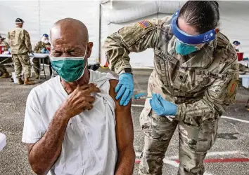  ?? AL DIAZ adiaz@miamiheral­d.com ?? Ralph Morris, 67, is injected with a COVID-19 vaccine by a U.S. Army medic during the opening day of the FEMA vaccinatio­n site on Miami Dade College’s North Campus on Wednesday.